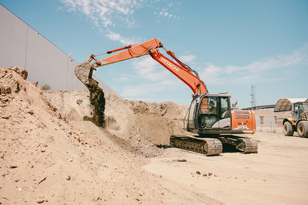 Excavator swinging a full bucket over the dirt pile