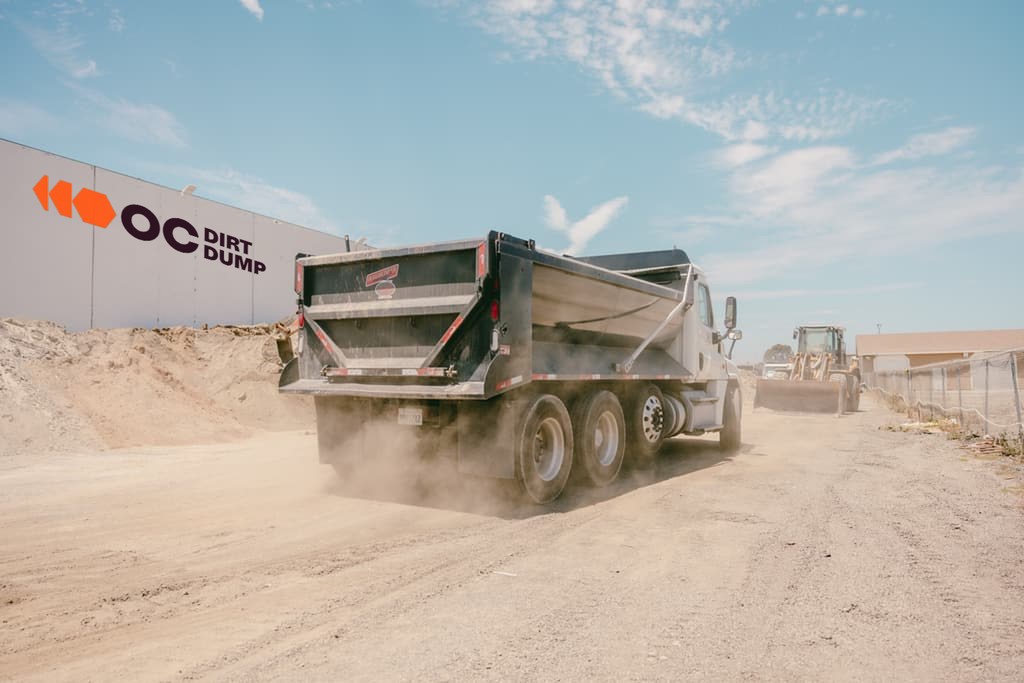 Dump truck rolling into the yard with dust coming off the tires